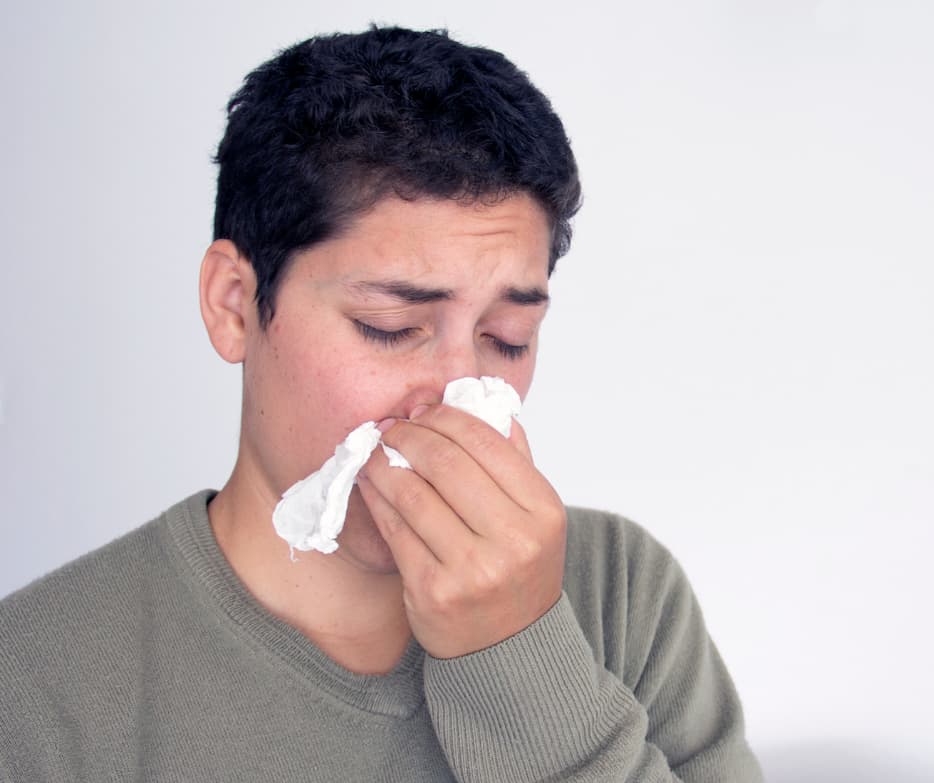 Person holding tissue on the nose to stop a nosebleed.
